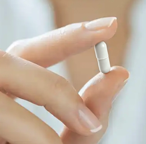 Close-up of a hand holding a single Lipozene capsule, highlighting the supplement’s size and appearance.